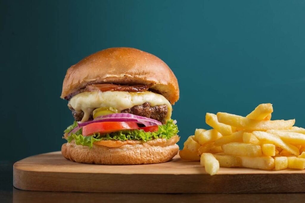 A cheeseburger and fries on a wooden board, fast food lunch option and showing how to improve eating habits