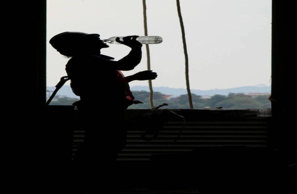 a silhouette of a man drinking from a bottle while at work, showing tradies to drink more water to stay Hydrated