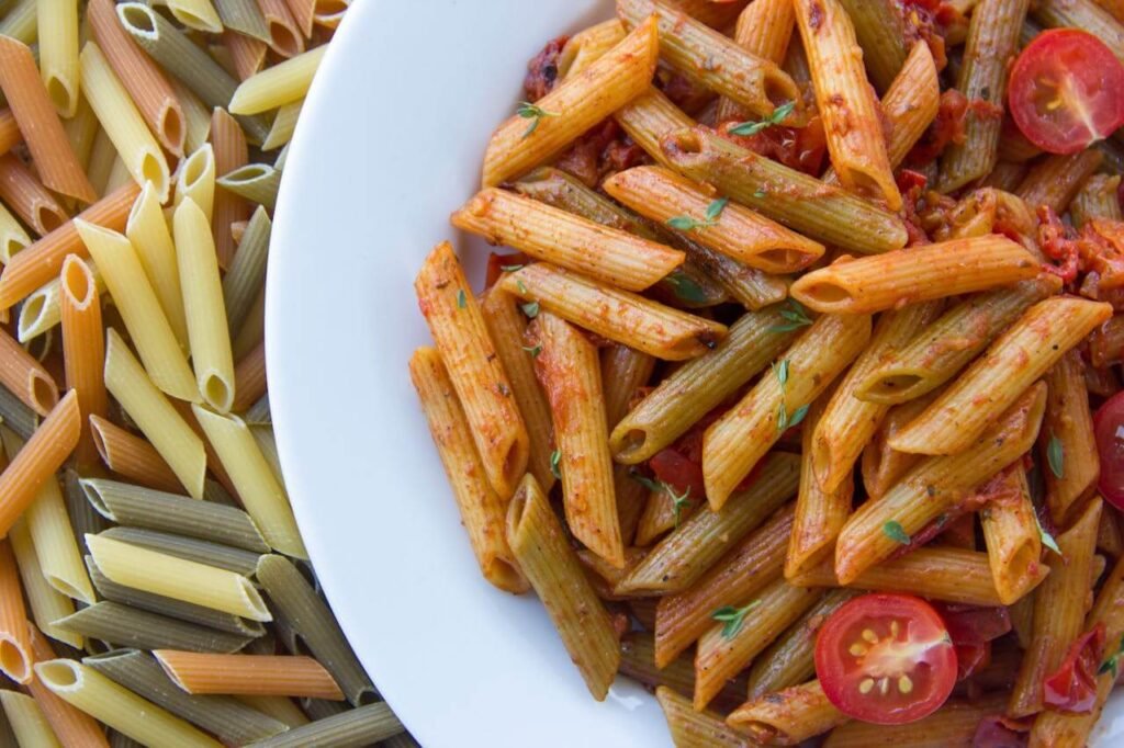 a plate of cooked and uncooked whole wheat pasta, showing a healthy Carbohydrates for tradies