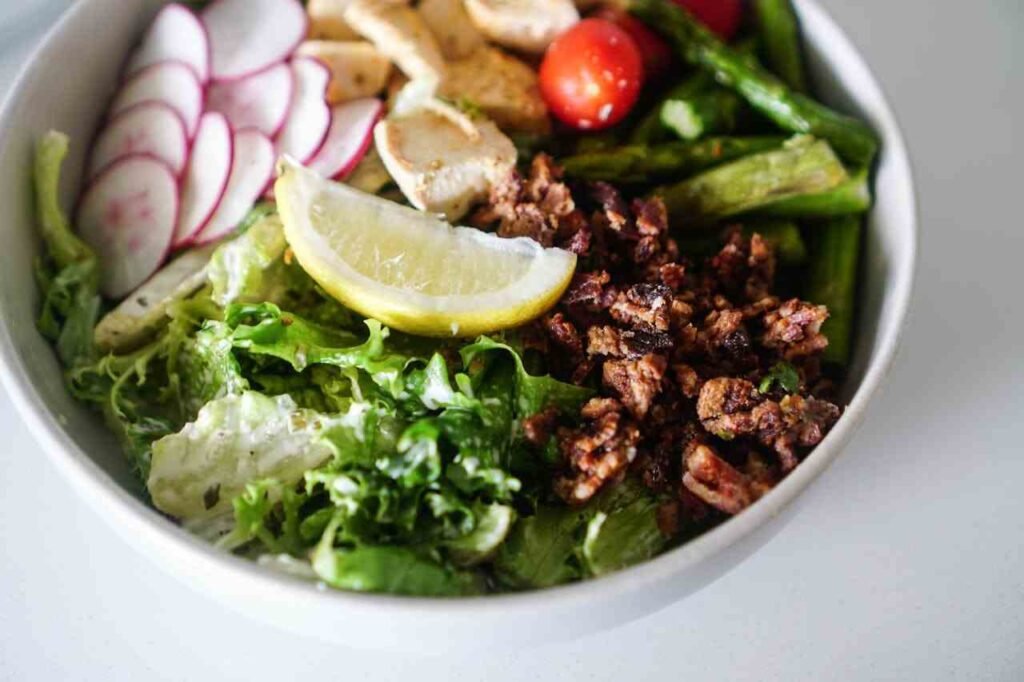 A filling and healthy salad in a bowl with lots of fresh vegetables and diced chicken.