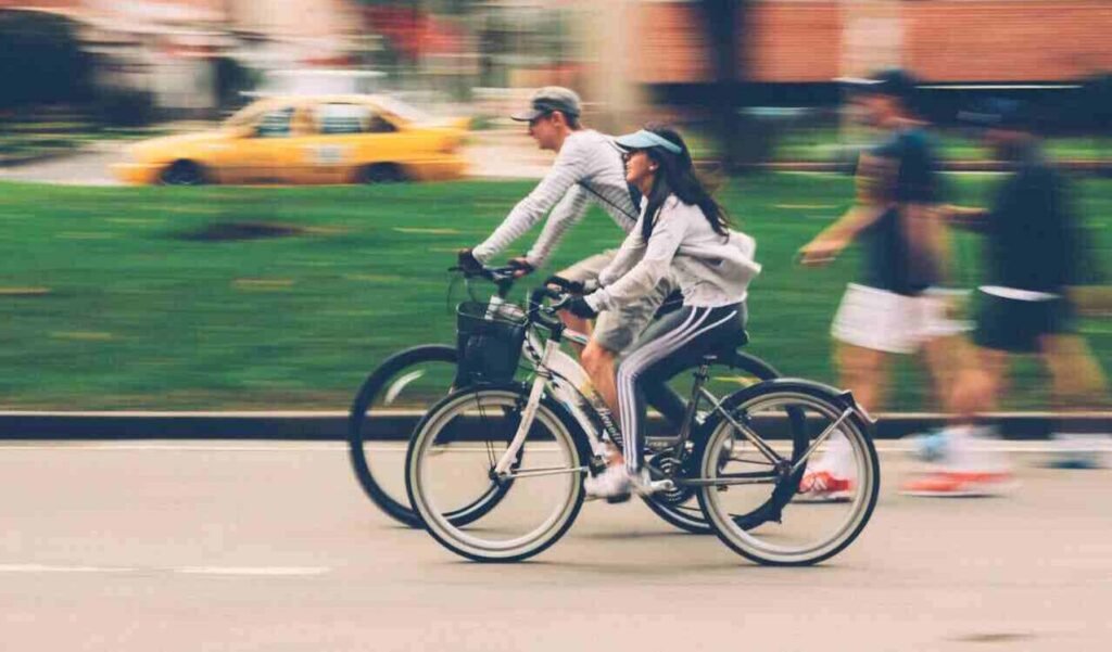 Two people riding bikes on a street, showing real life scenarios, exercise and fitness.
