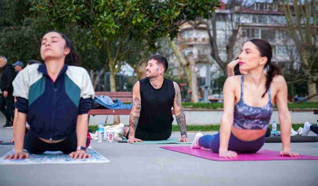 Three people doing yoga stretches in a park.