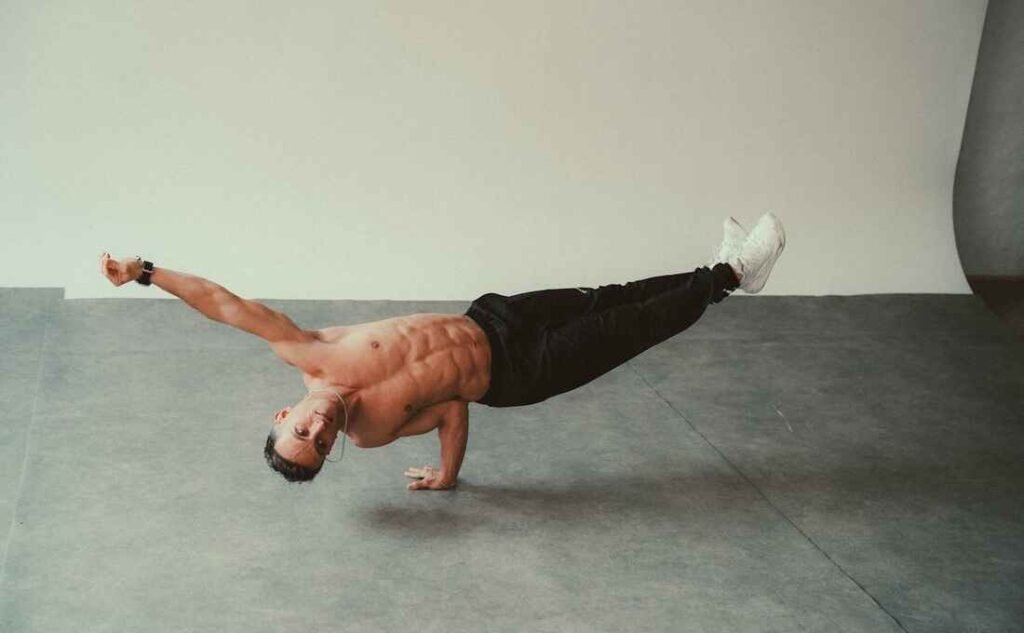 A guy doing calisthenics, doing a balancing skill on one hand
