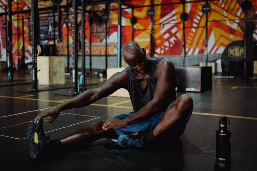 Guy stretching on the floor of a gym, as part of recovery.