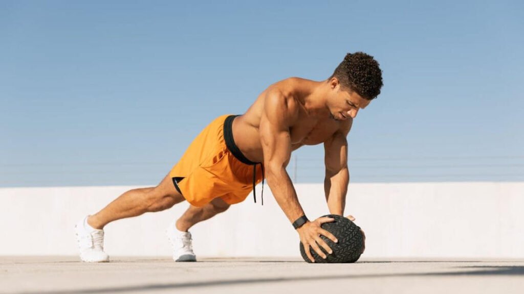 Strong looking guy with muscular strength, doing pushups on a med ball.