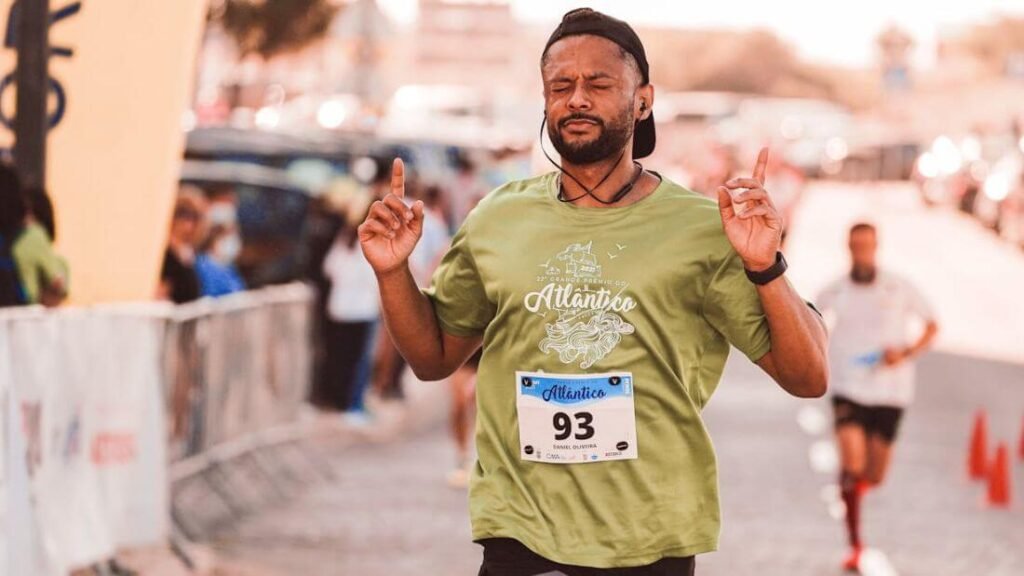 A guy running in a road race, with his eyes closed listing to music, pointing up to the sky representing pointing to the Minimum Effective Standards.