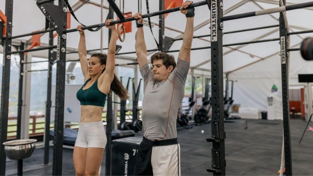 Male and female athletes performing pull-ups in a gym, illustrating hybrid strength standards.