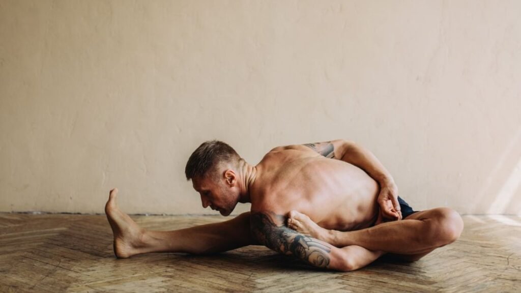 Man seated in a deep hamstring and hip stretch
