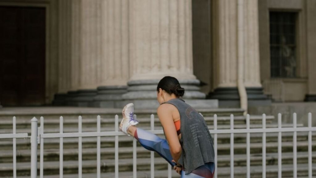 woman stretching her hamstring on a fence
