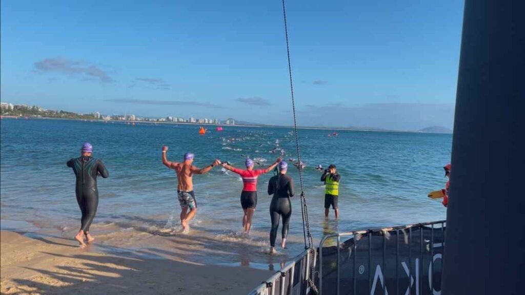 Four people getting into the ocean to start there race.