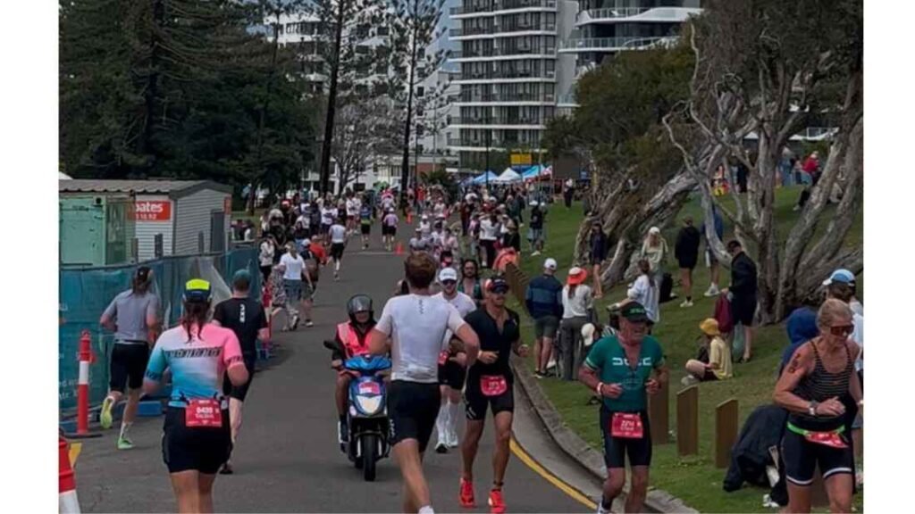 lots of athletes running during the sunshine coast Half Ironman, with crowds of supporters on the side.
